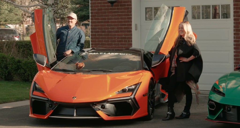 Hosts with orange Lamborghini Revuelto scissor doors open at the event