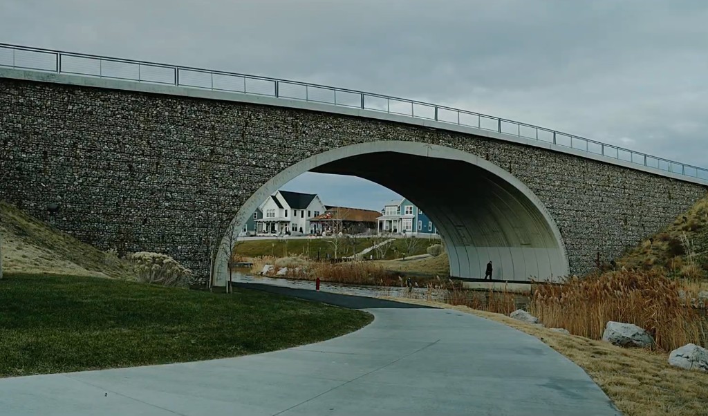 Stone bridge arch framing a white house along a park path